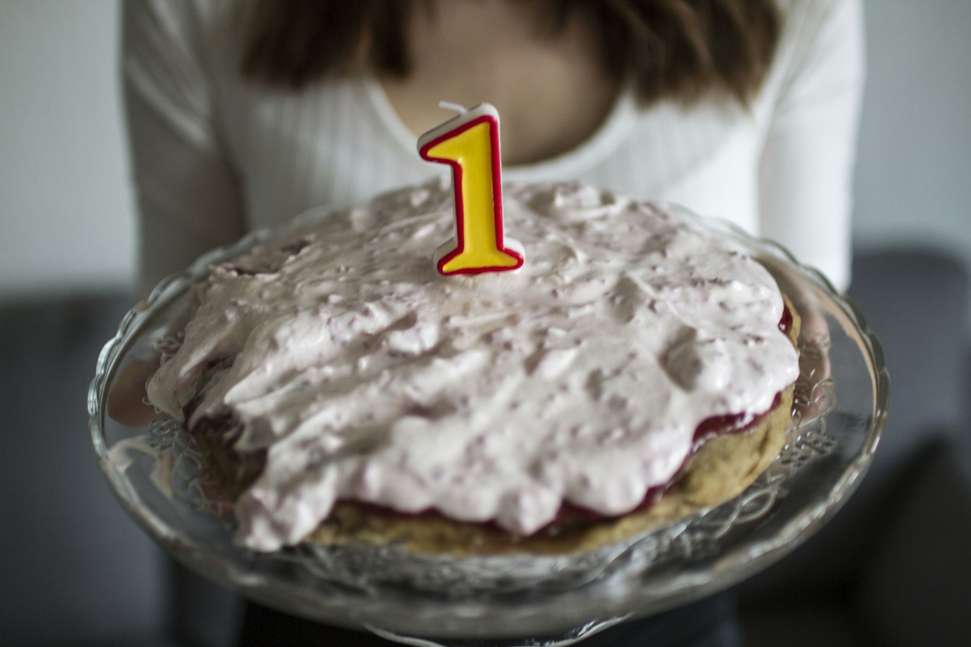Pessoa segurando um bolo de aniversário com vela de número um